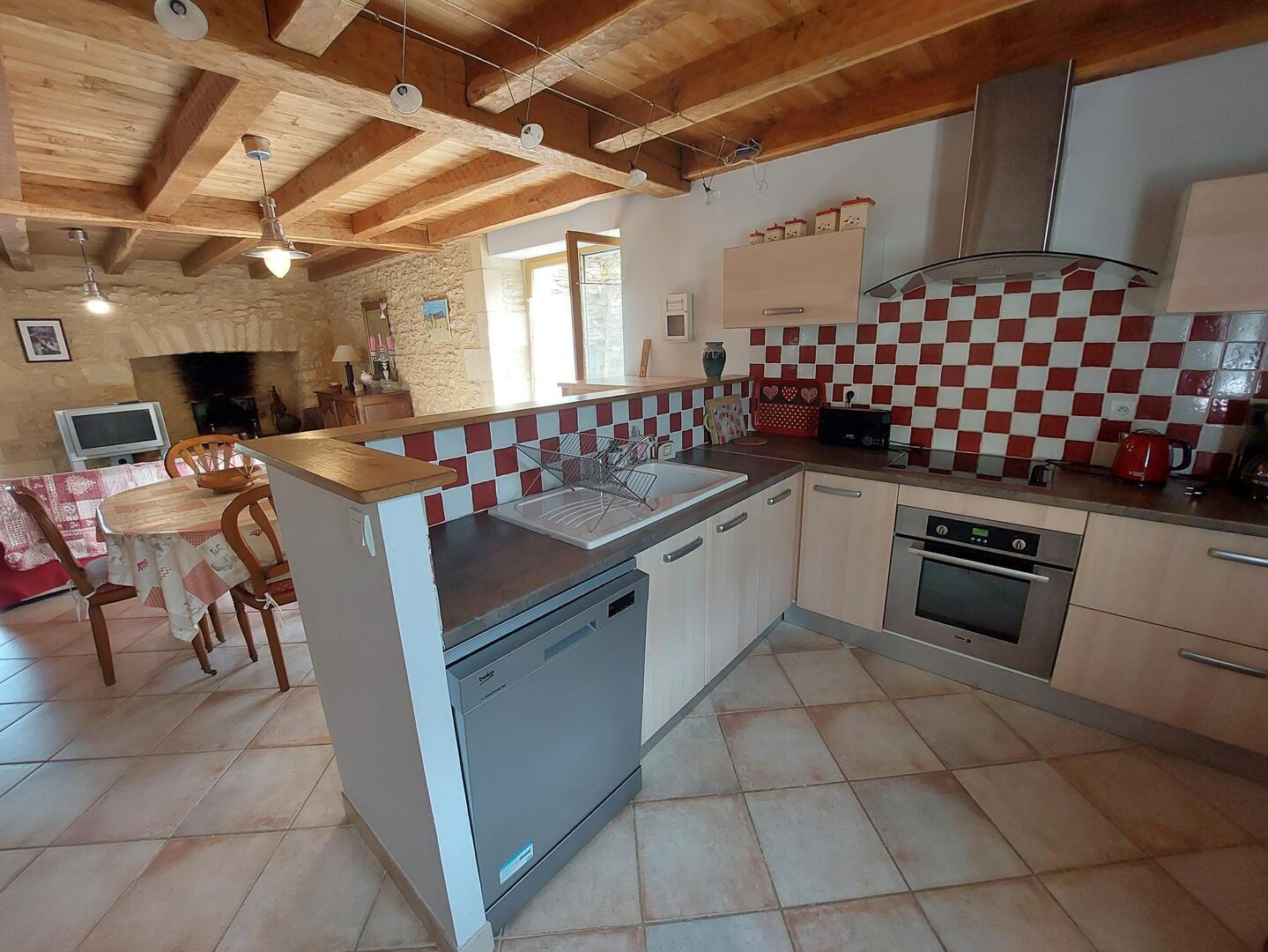 Cuisine ouverte équipée avec îlot central et carrelage damier rouge, gîte Sarlat