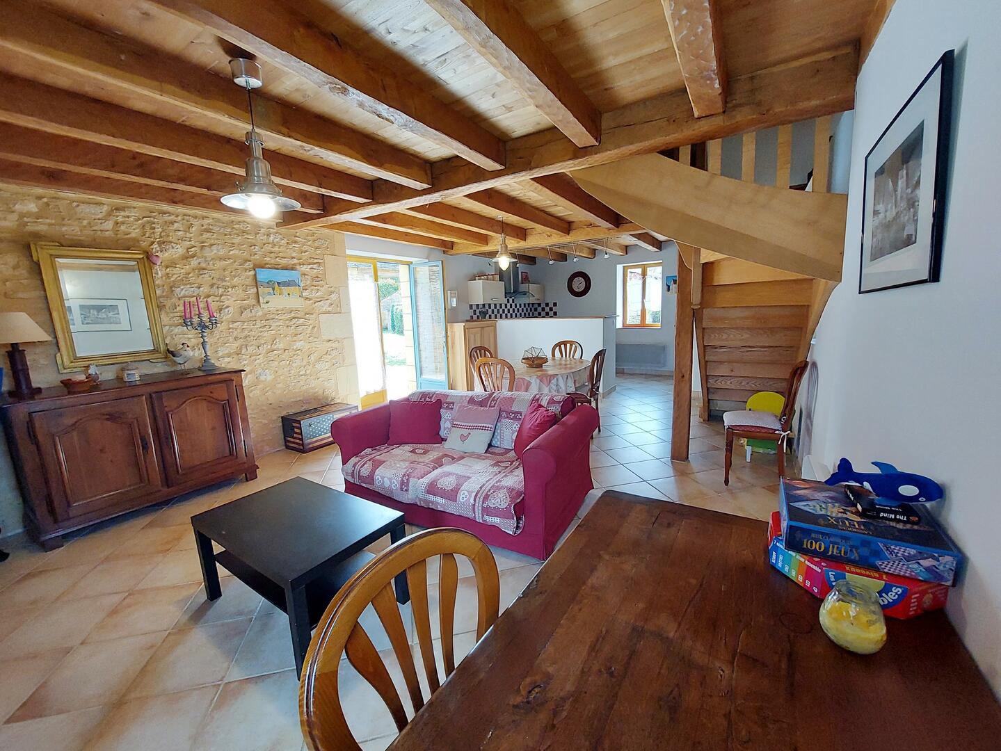 Salon avec poutres apparentes, murs en pierre et table à manger, gîte Sarlat