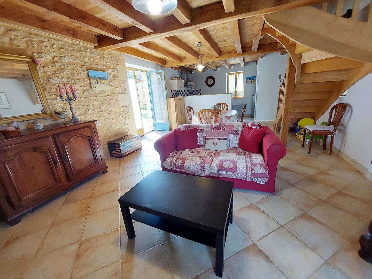 Salon séjour côté canapé et escalier en bois, gîte location Dordogne